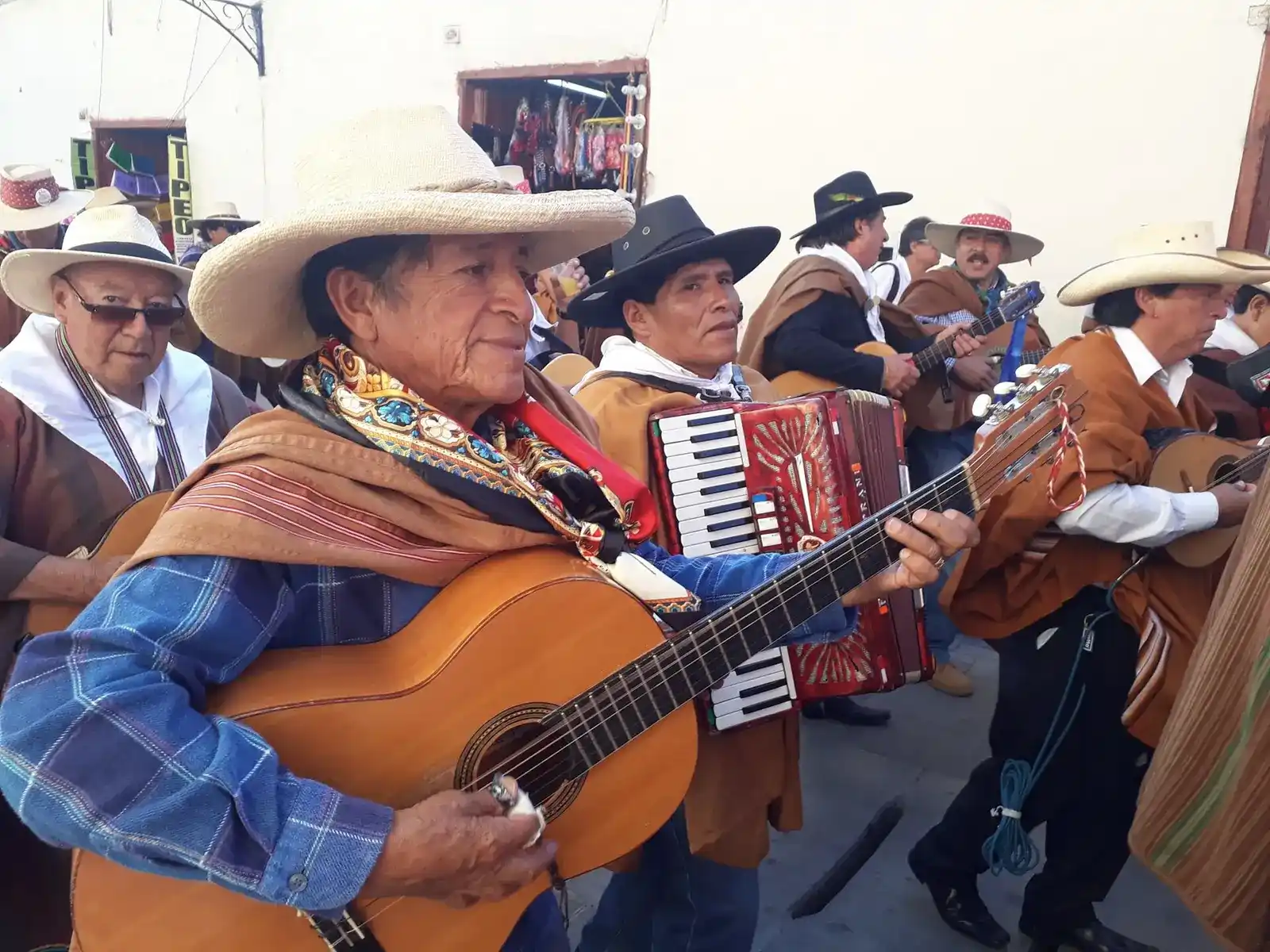 Músicos con ponchos, sombreros, guitarras y acordeón tocando en la calle durante el carnaval de Ayacucho.